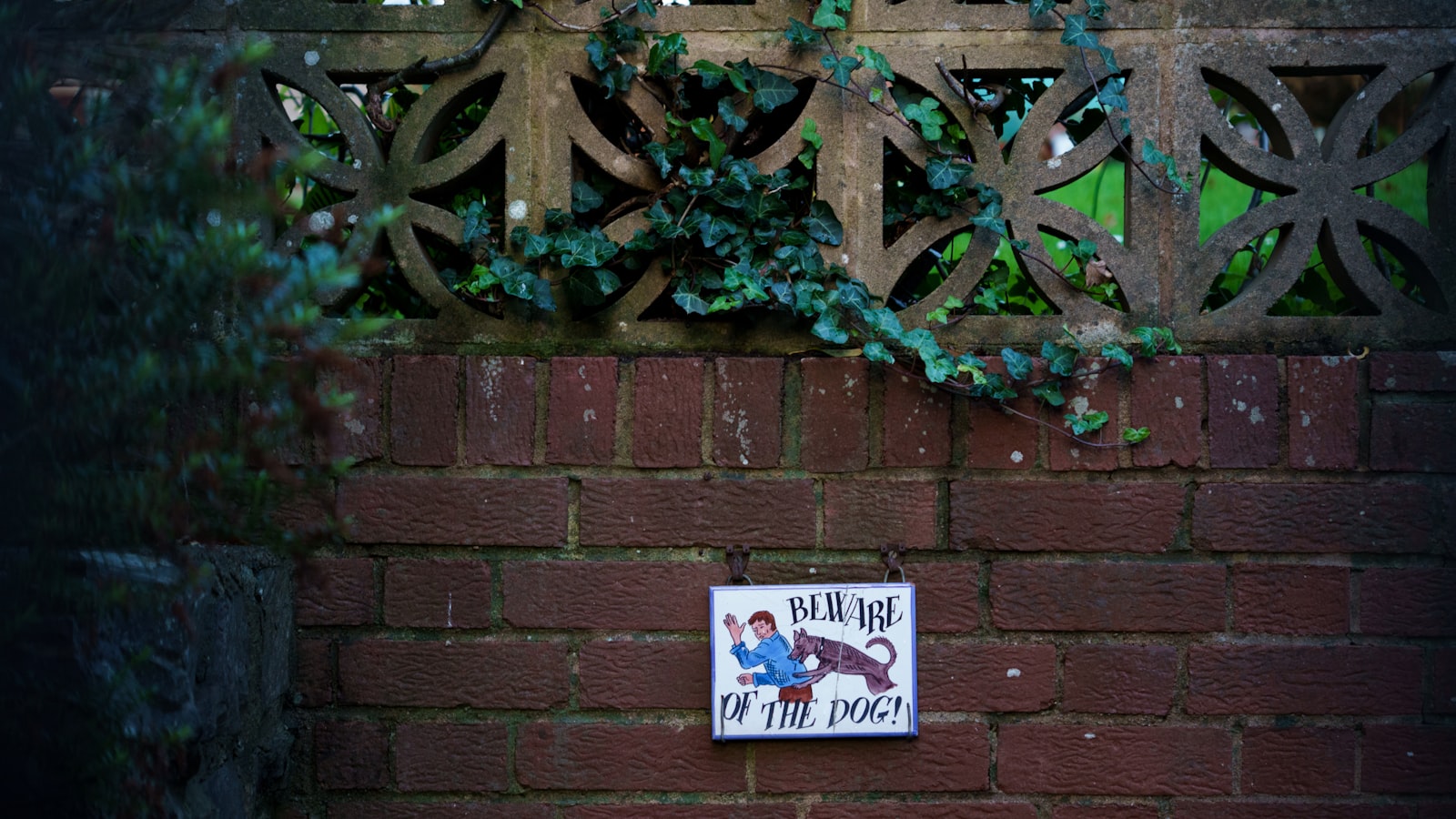 A beware of the dog sign fixed to a brick wall