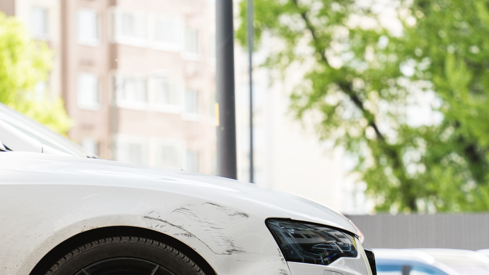 Scrape damage along the fender of a parked white car
