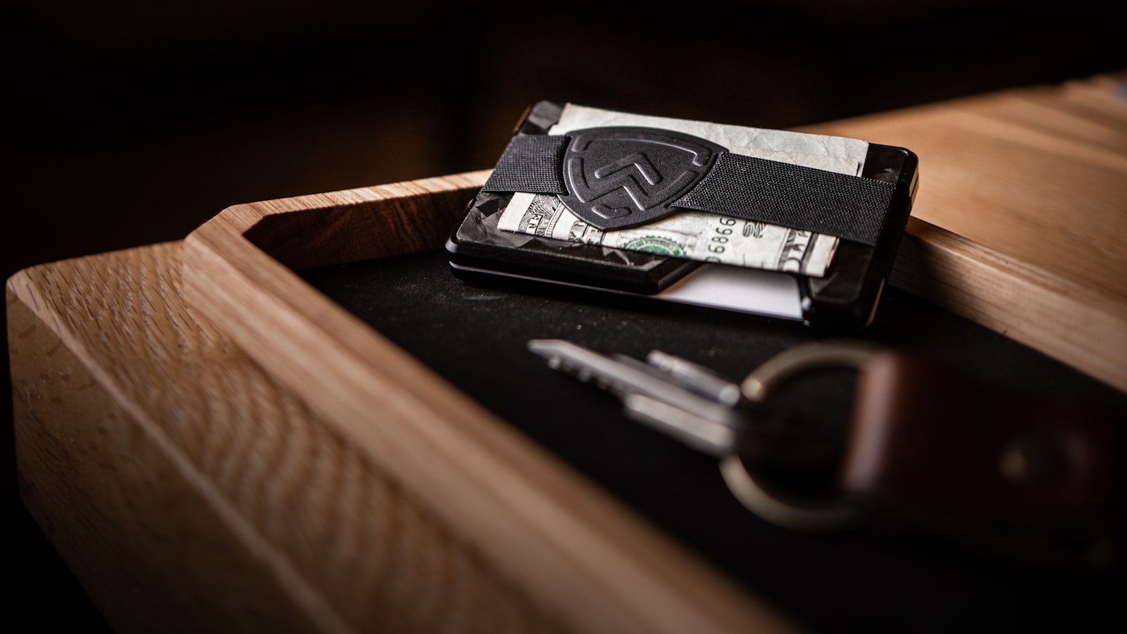 A wallet and keys sitting in a wooden tray