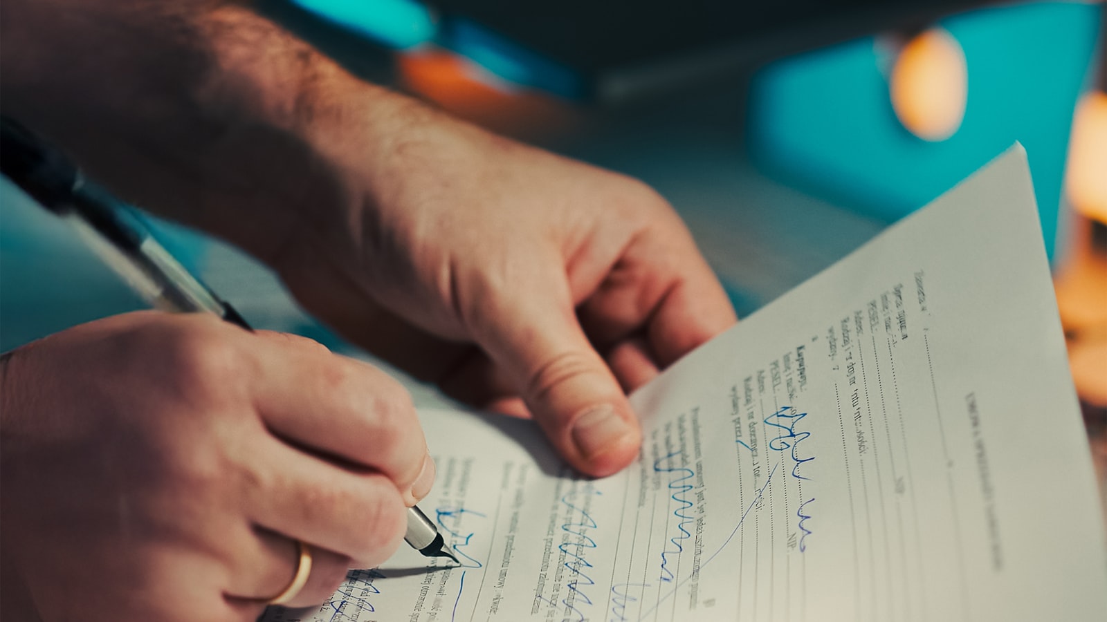 A hand signing a document with a fountain pen