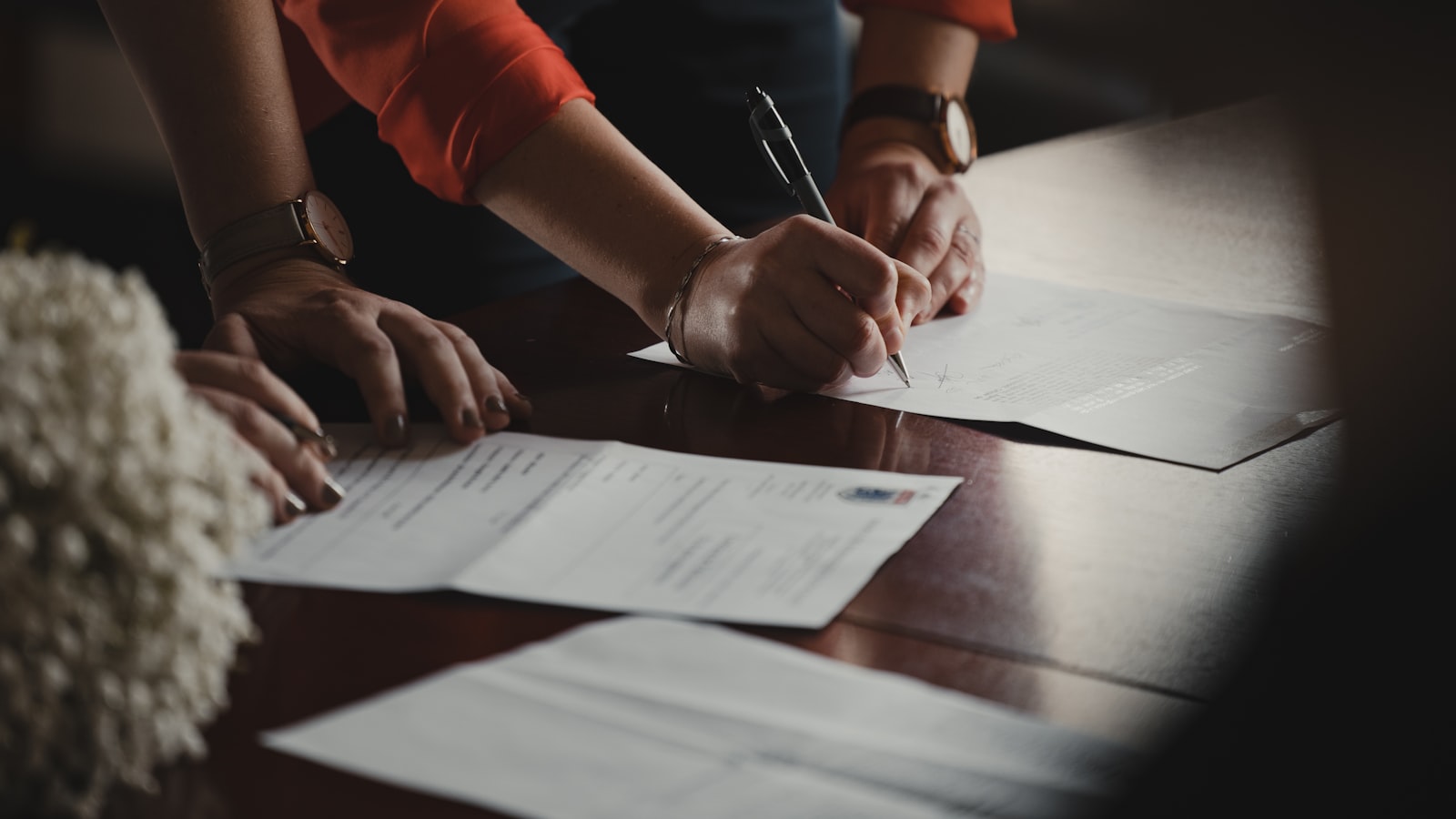 Two people signing paperwork across a desk
