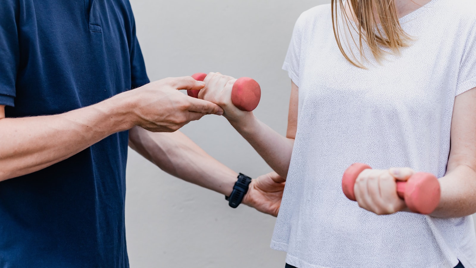 A physiotherapist guiding a patient through a dumbbell exercise