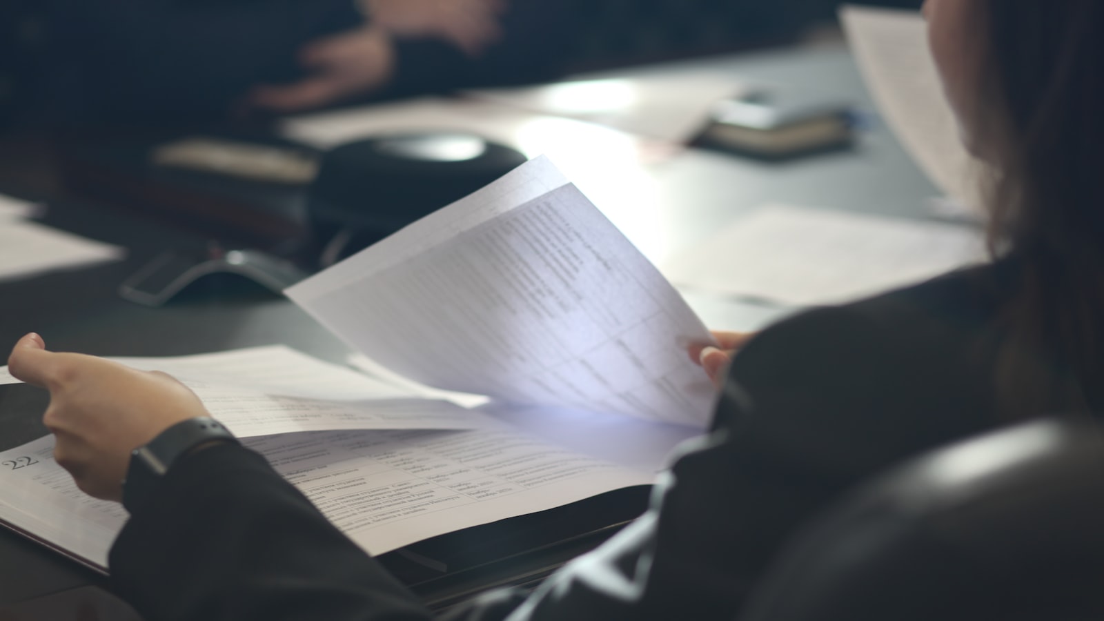 A woman reading a document across a meeting table