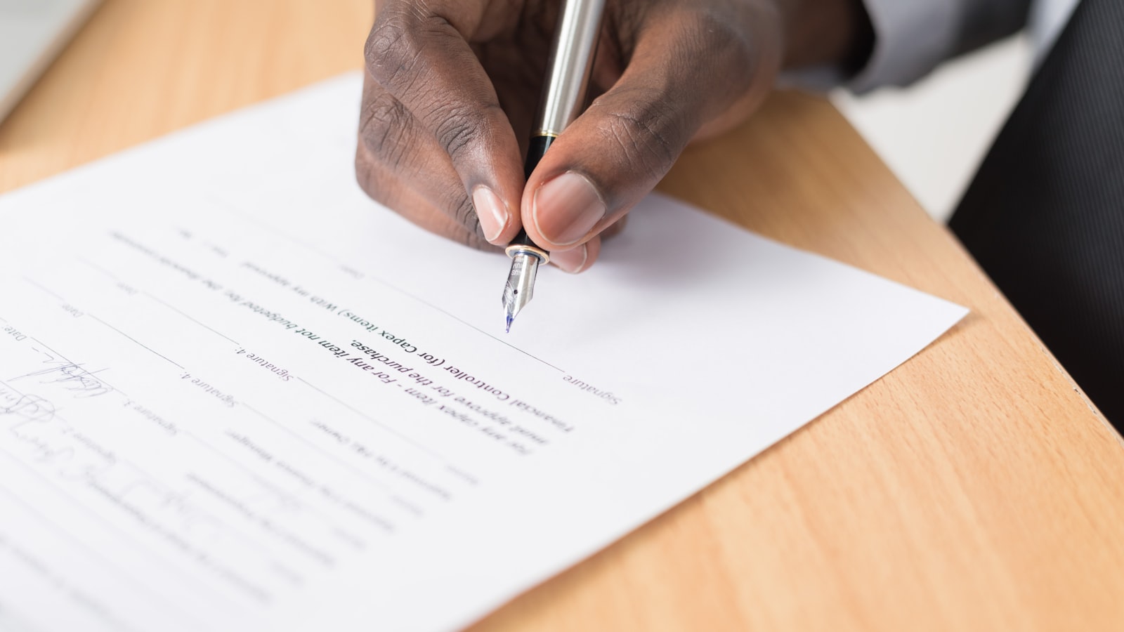 A hand signing an agreement with a pen